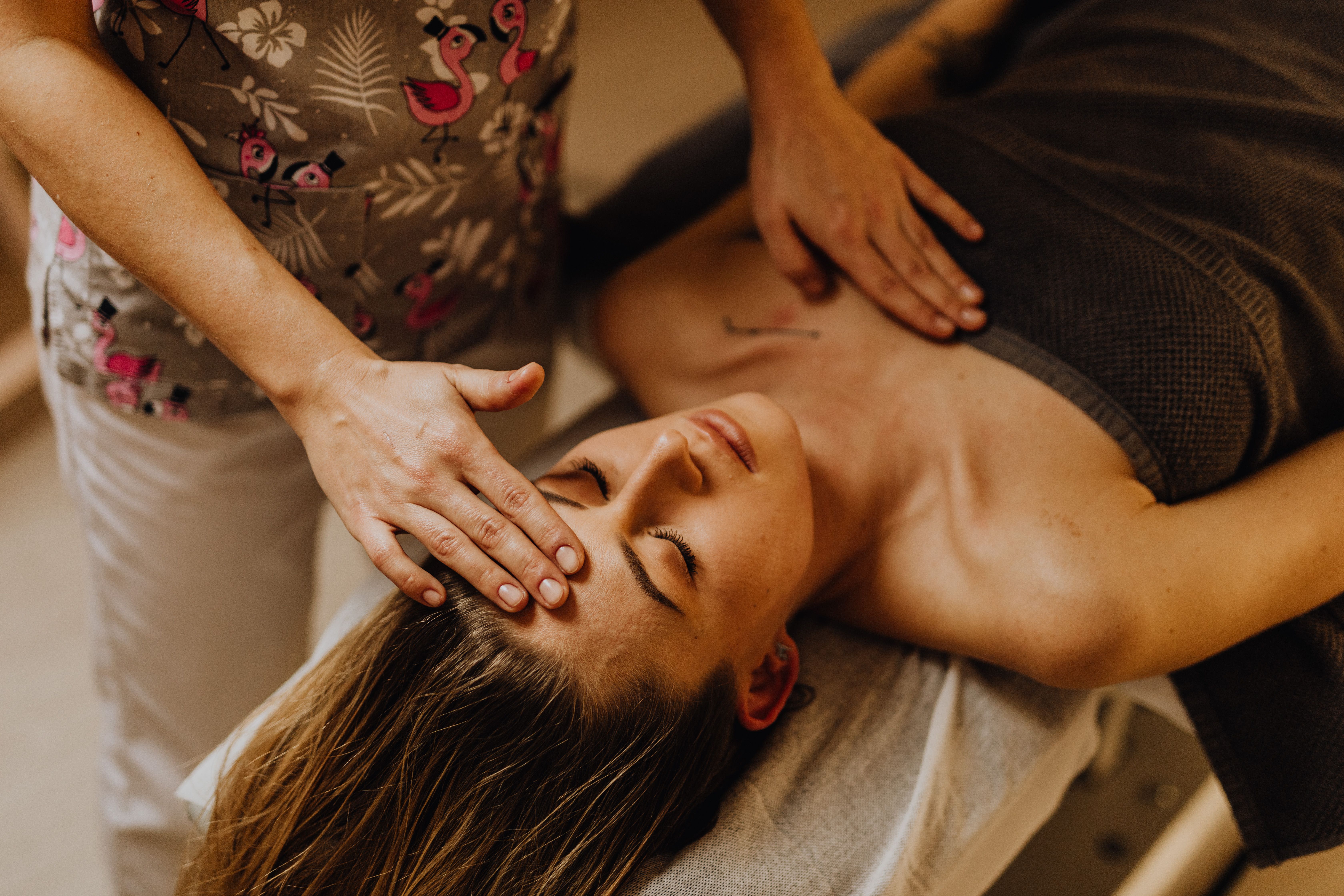 A Reiki practitioner placing hands gently on a client's head and chest during a healing session.