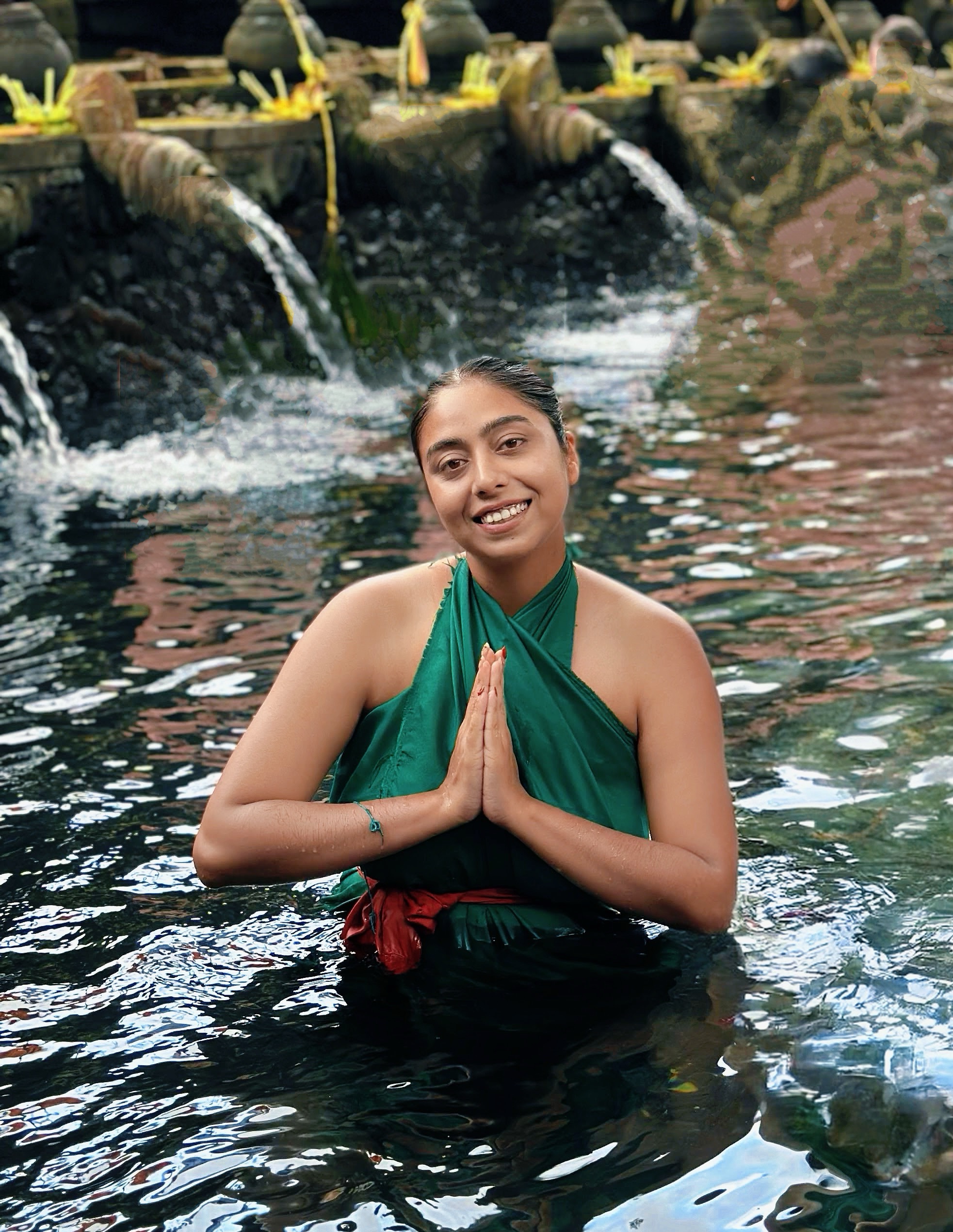 Shefali Nath with hands in namaste, standing in the sacred water at a Balinese temple.